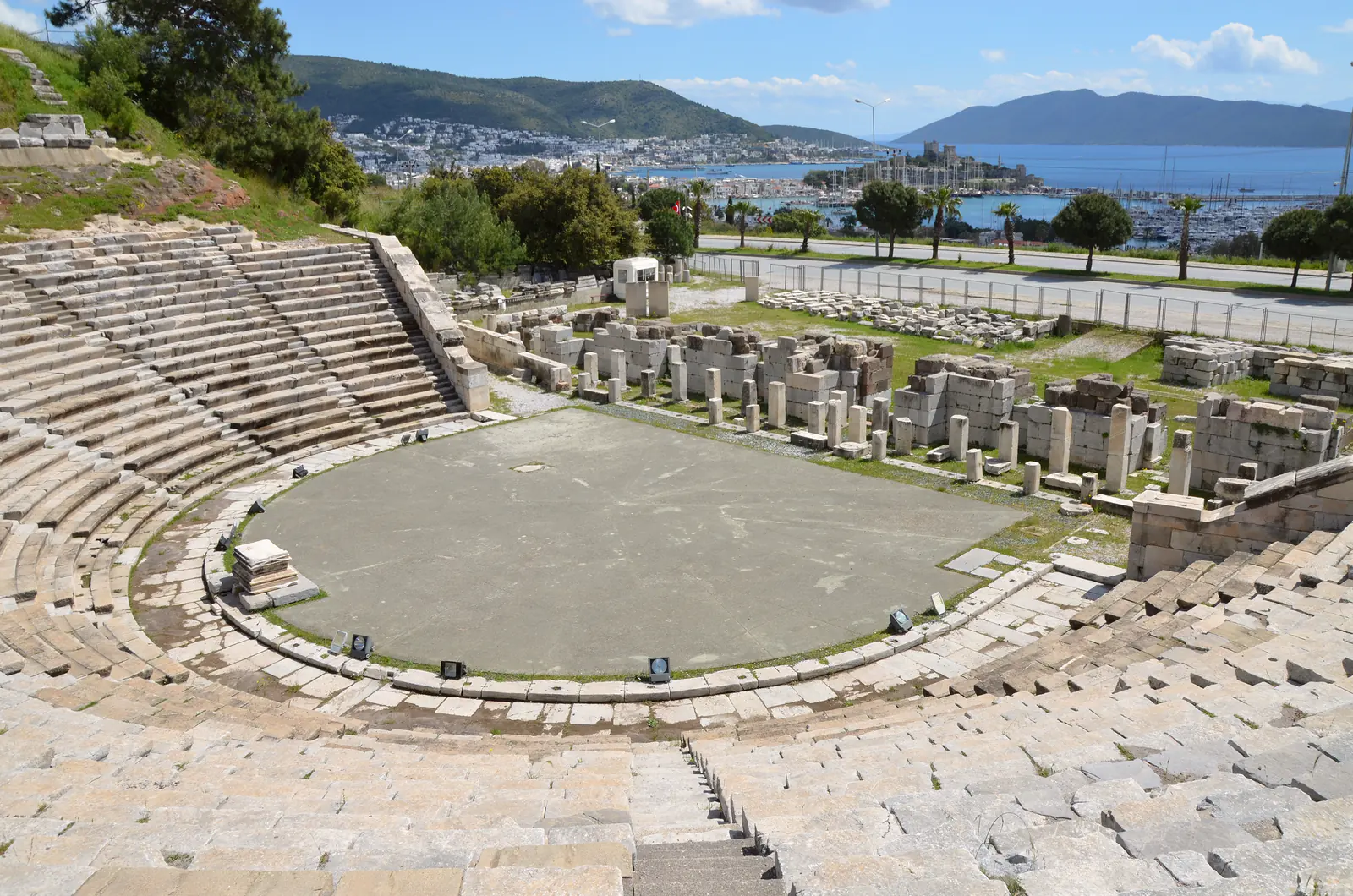 Bodrum Antik Tiyatrosu'nun taş basamakları ve orkestrası, arkada Bodrum limanı, kale ve Ege
